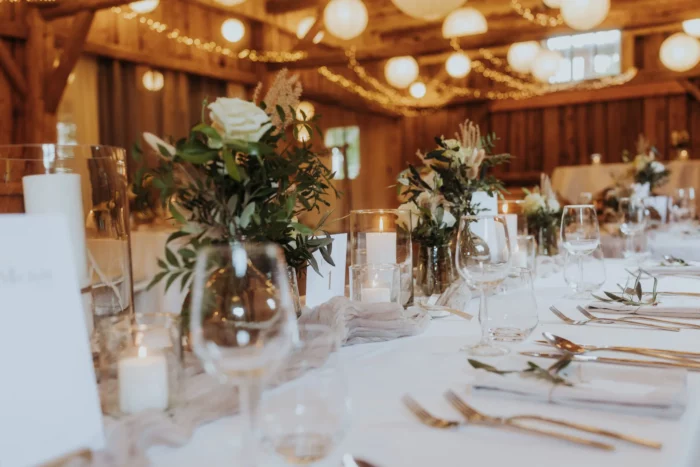 Gedeckte Hochzeitstafel mit Eukalyptus und Lichterketten im Holzstadl