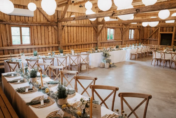Lange Hochzeitstafeln im Holzstadl mit Holzwänden und Lampions