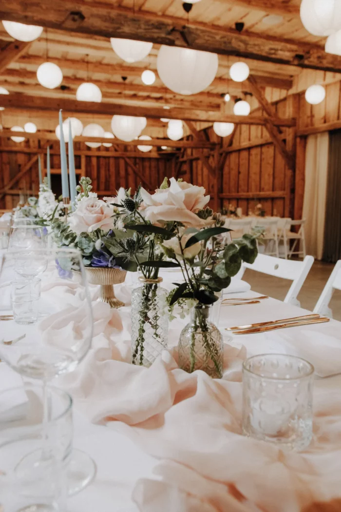 Tischdeko mit weißen Blumen auf der Hochzeitstafel im Holzstadl
