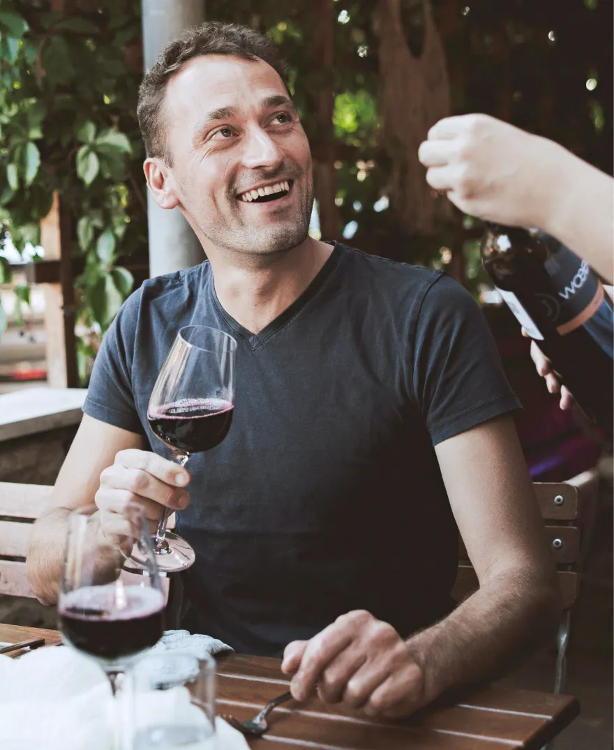 Gast mit Rotwein bei einer Firmenfeier im Gastgarten