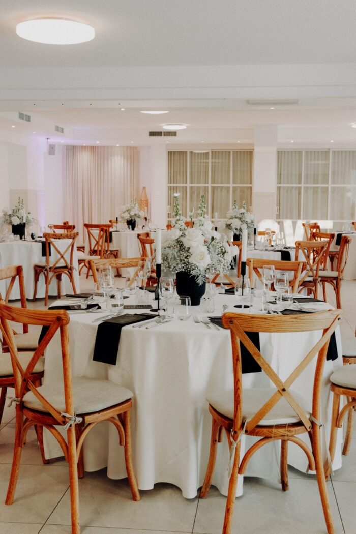 Festsaal des PreunerWirt für Hochzeiten mit runden Tischen, Holzstühlen und Blumenschmuck