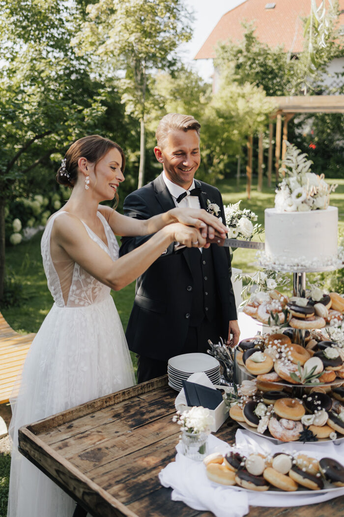 Brautpaar schneidet die Hochzeitstorte im Garten an