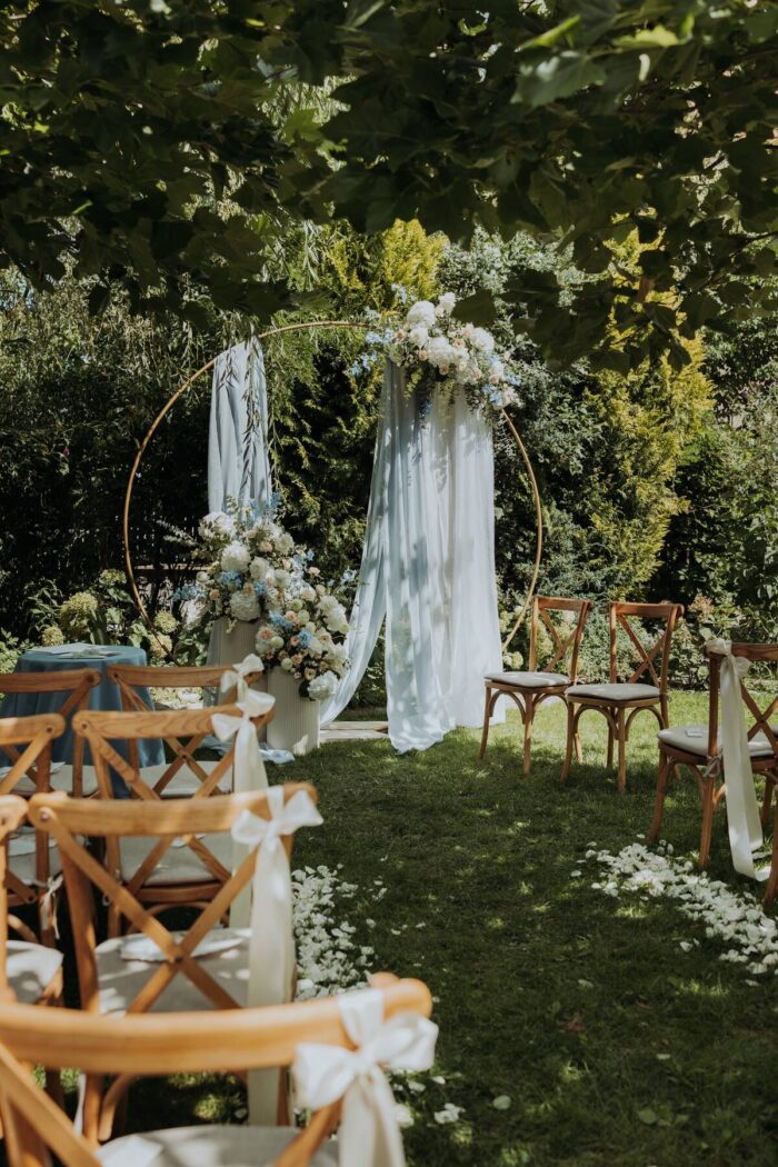 Trauungsbogen mit Stoff und Blumen im Garten