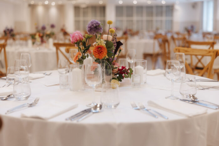 Runder Hochzeitstisch mit weißer Tischwäsche und bunten Blumen im Festsaal des PreunerWirt