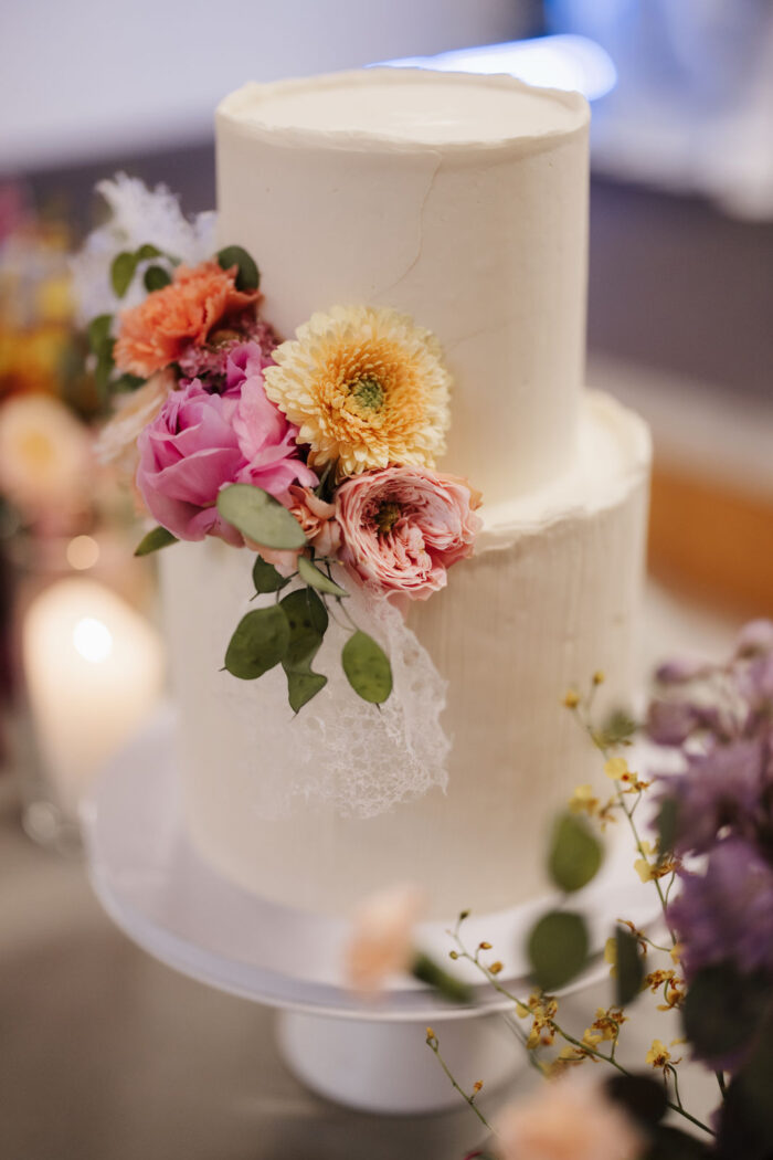 Weiße zweistöckige Hochzeitstorte mit bunten Blüten – Hochzeit Hemetsberger beim PreunerWirt