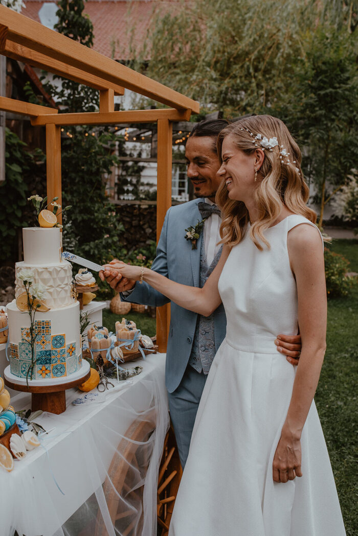 Brautpaar schneidet die Hochzeitstorte mit Majolika-Fliesenmuster und Zitronen an