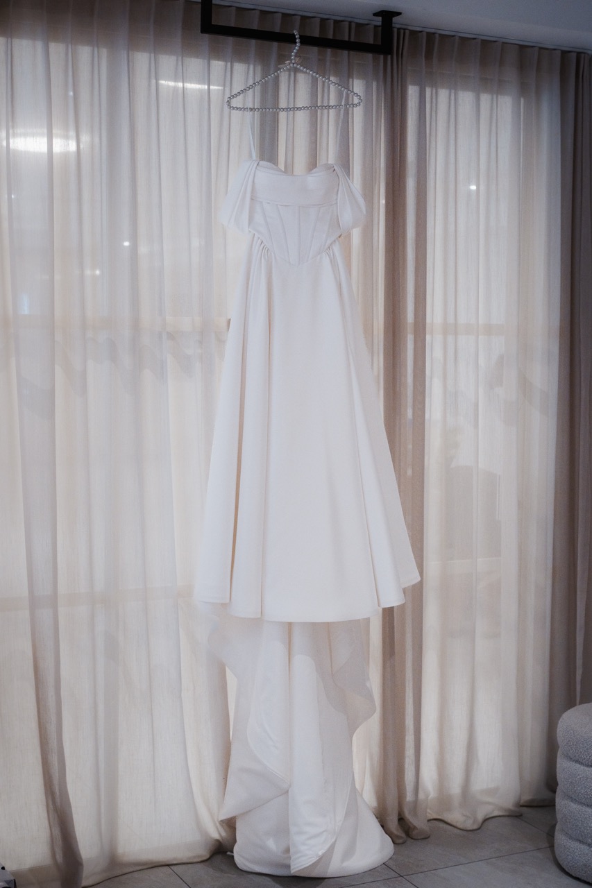 Brautkleid von Maria hängt beim Getting Ready am Fenster