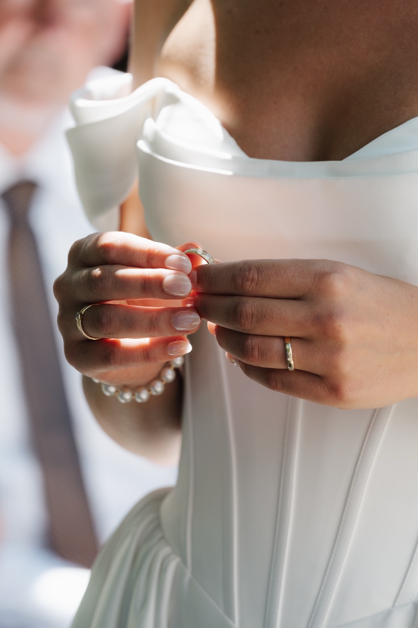 Detail von Marias Hand mit Ehering am Brautkleid