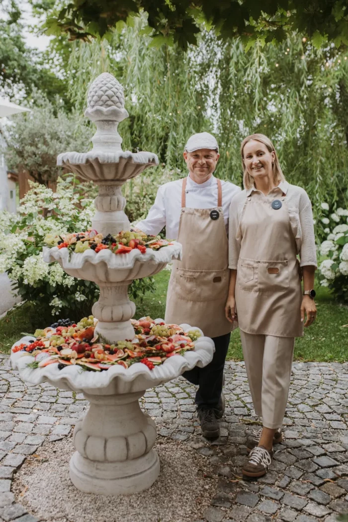 Eva und Mario Schiller-Preuner am Brunnen mit Agape-Buffet im Hochzeitsgarten