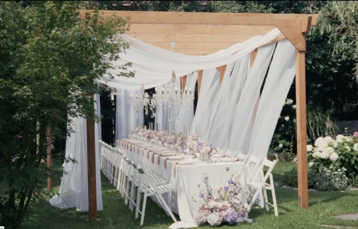 Festlich gedeckte Hochzeitstafel unter weißen Stoffbahnen im Hochzeitsgarten des PreunerWirt